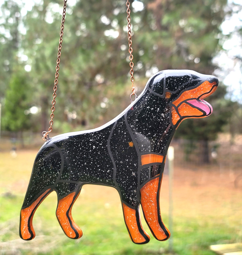 cremation ash Rottweiler, glass dog sun catcher memorial, ash-infused Rottweiler urn, kiln-fused Rottweiler, pet ashes dog keepsake, handmade Rottweiler cremation art, dog sun catcher with ashes  hanging from copper chain in your garden