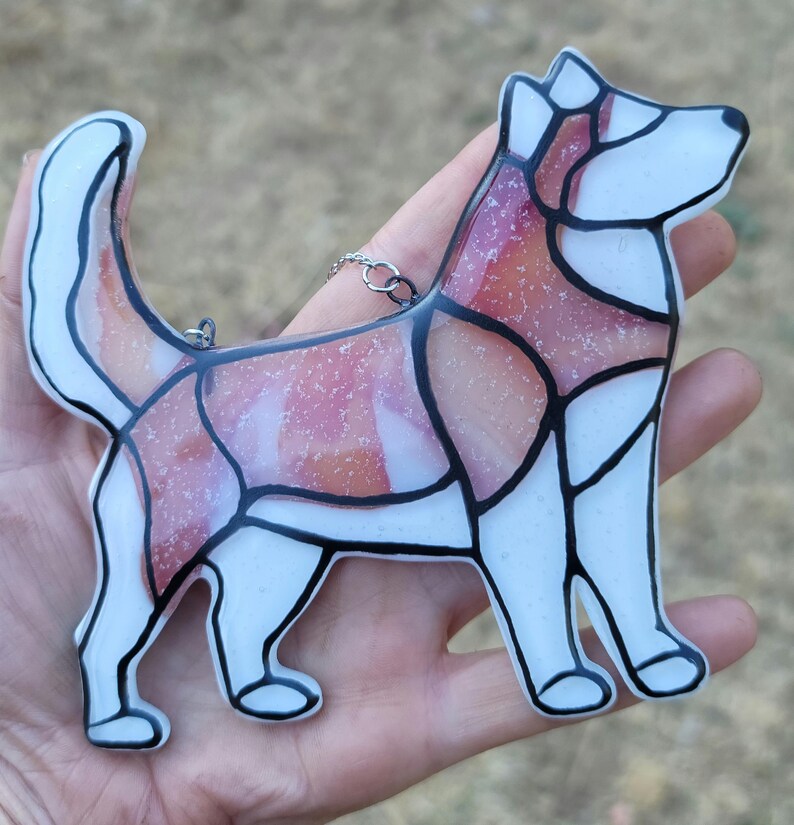 Red Husky Glass Urn Ashes-Infused-Glass Ornament   A hand holding  glass cremation urn suncatcher with a silhouette of a Husky dog with cremation ashes inside. infusion glass artist Joele Williams ashes infused glass
